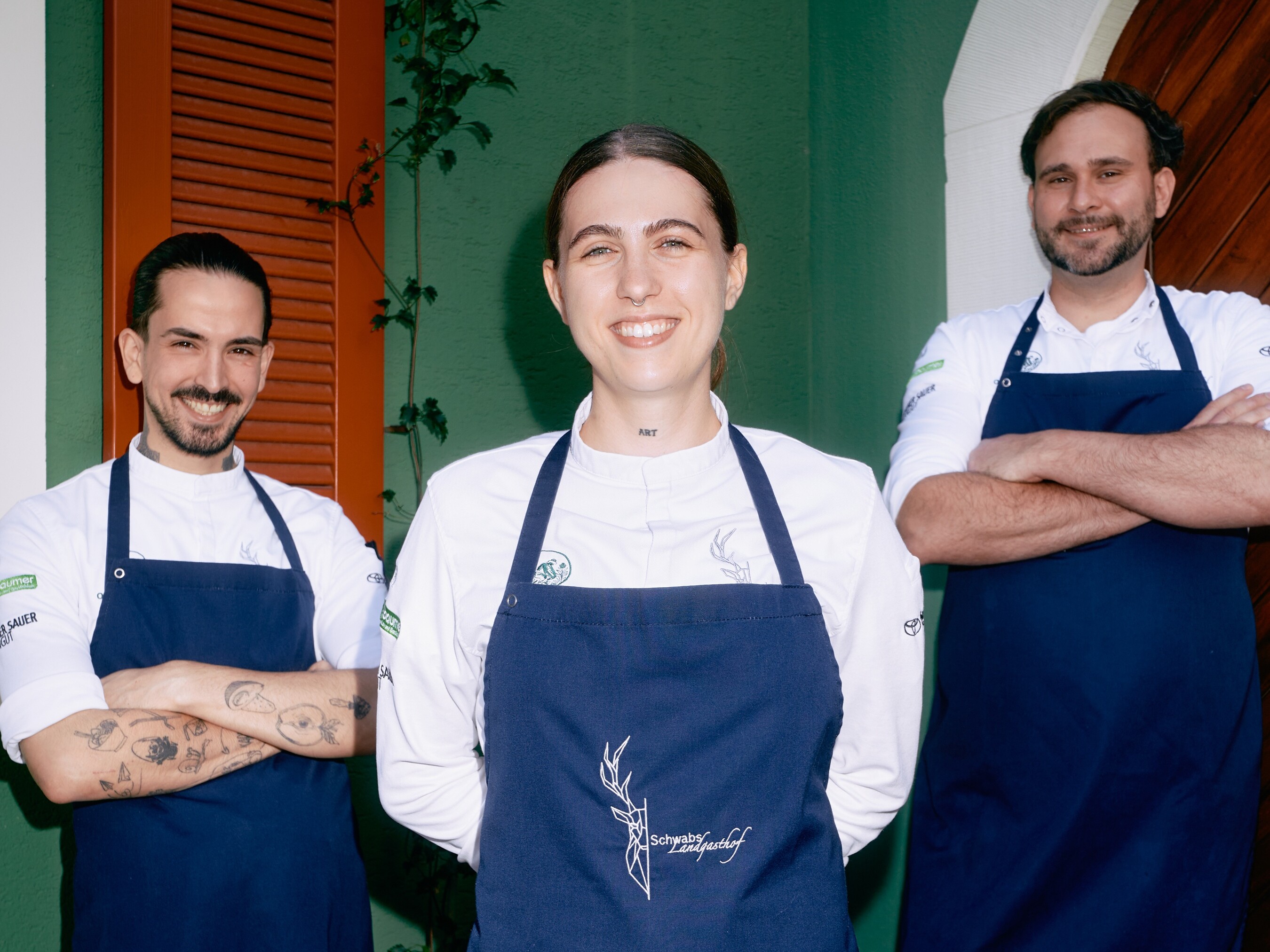Luca Vitale, Melina Vitale und Nicolas Frank Eine Gruppe von Menschen in Schürzen lächelt.